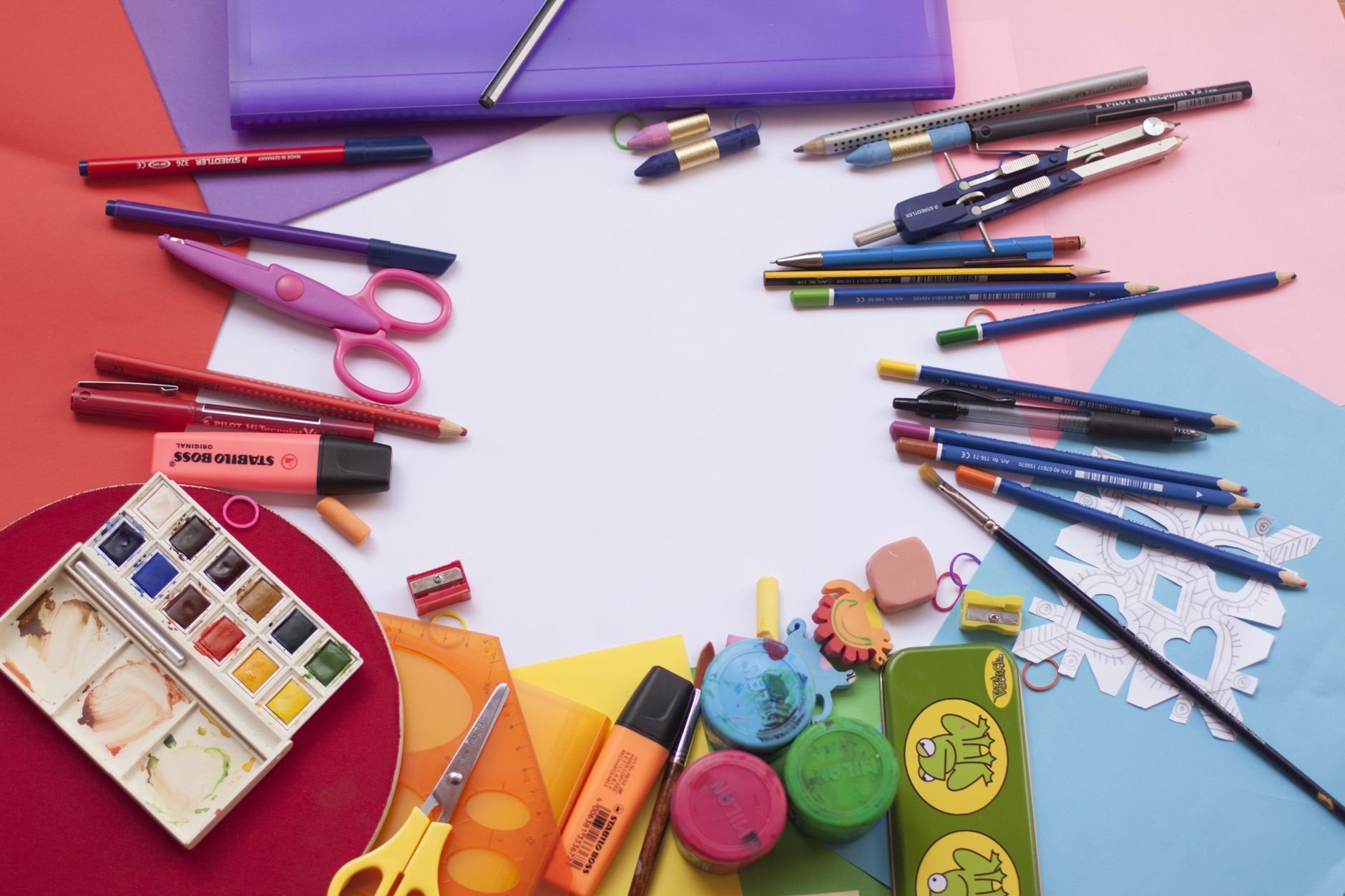 A vibrant selection of school supplies on a desk, including paints and stationery.