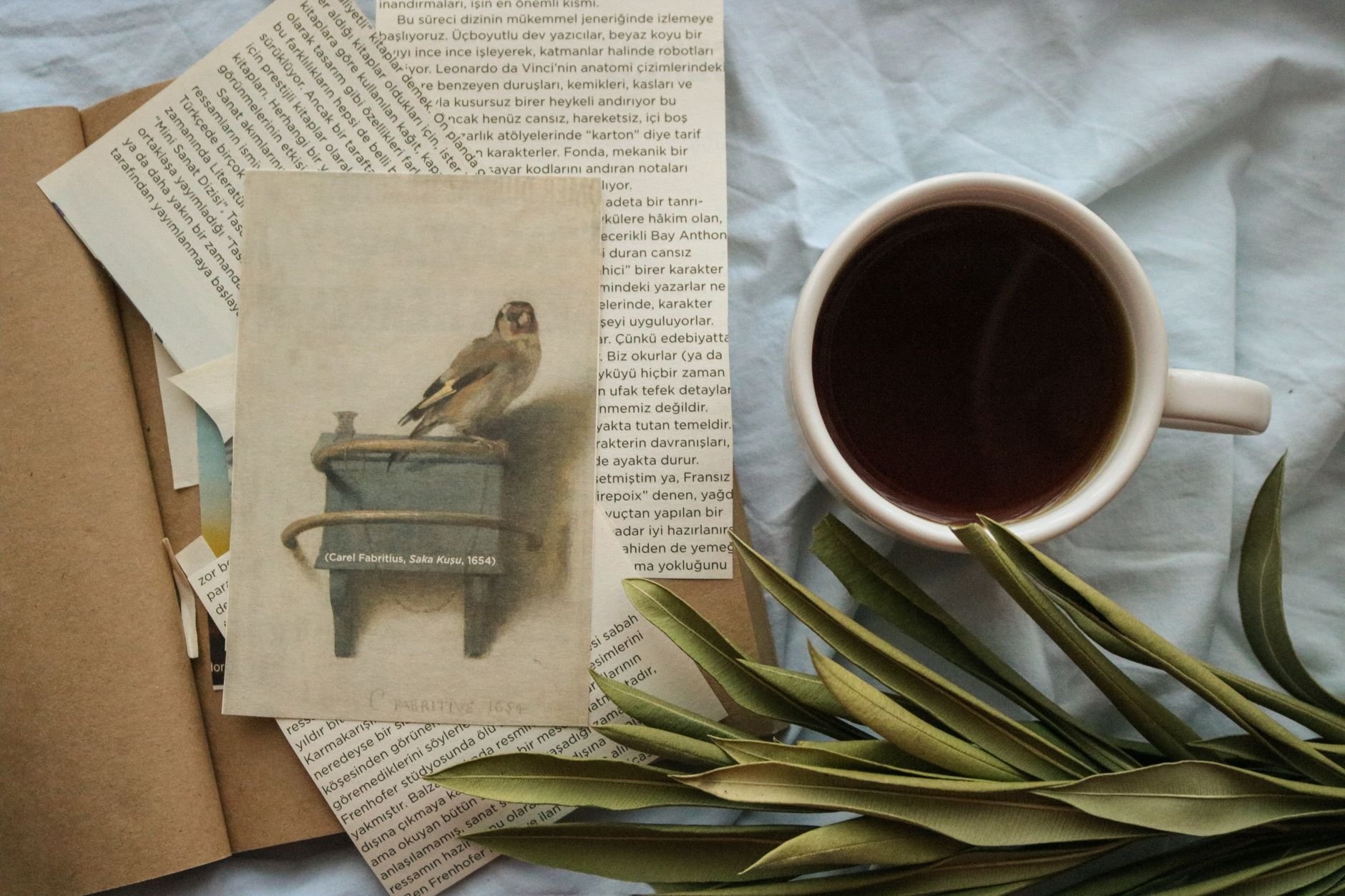 Flat lay of coffee cup, art print, and papers, invoking a cosy atmosphere.